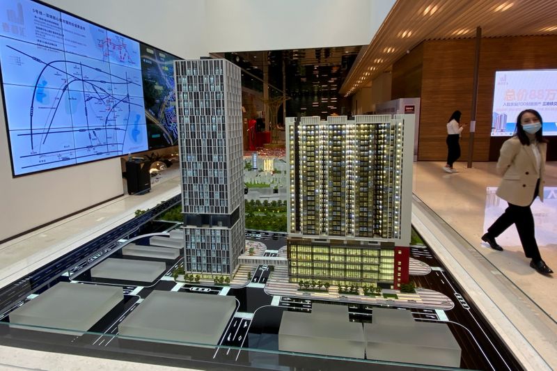FILE PHOTO: Woman walks past a property model at a sales office of Kaisa Group Holdings Ltd in Shenzhen