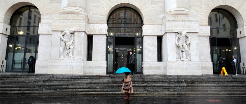 Una donna passa accanto alla sede della Borsa di MIlano