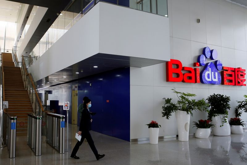 FILE PHOTO: People walk near a Baidu logo at the company headquarters in Beijing