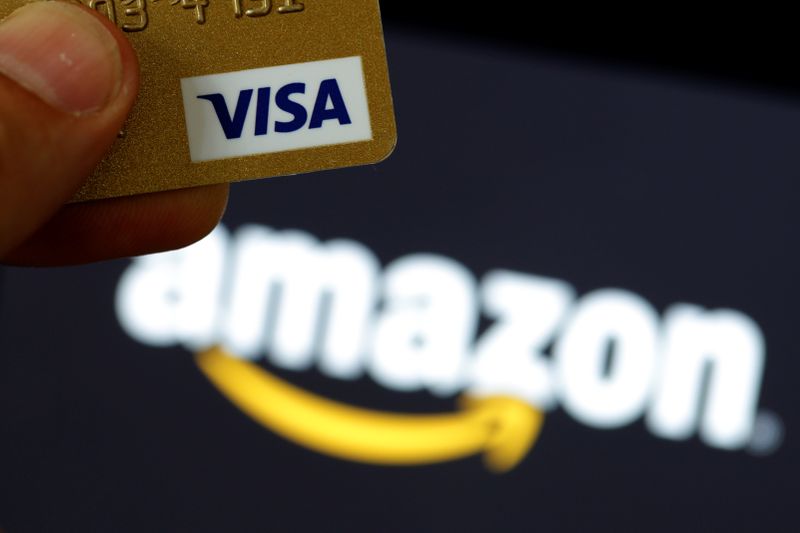 Una tarjeta de crédito visa ante un logotipo de Amazon