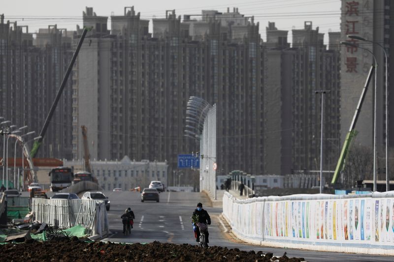 FILE PHOTO: Man rides a bicycle next to a construction site near residential buildings in Beijing