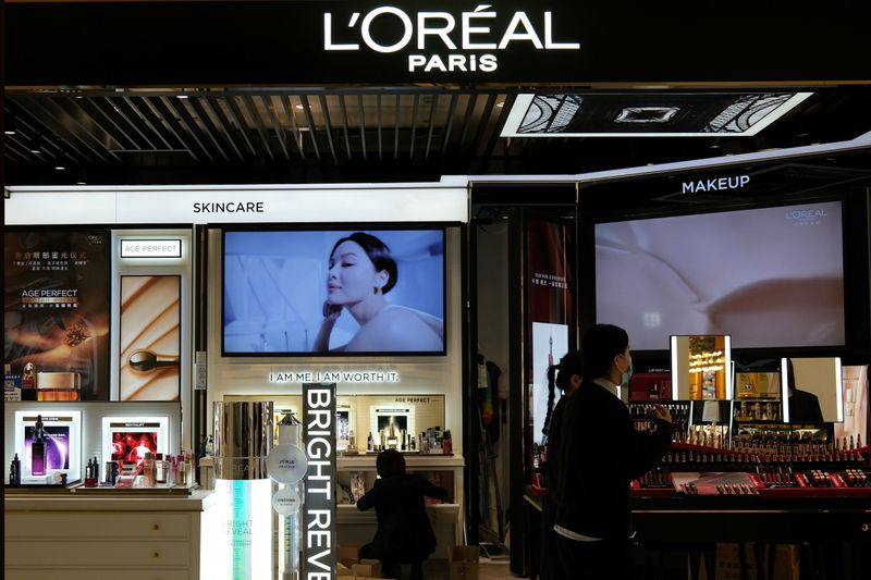FILE PHOTO: Staff members work at a counter of cosmetics brand L’Oreal at a shopping mall in Beijing