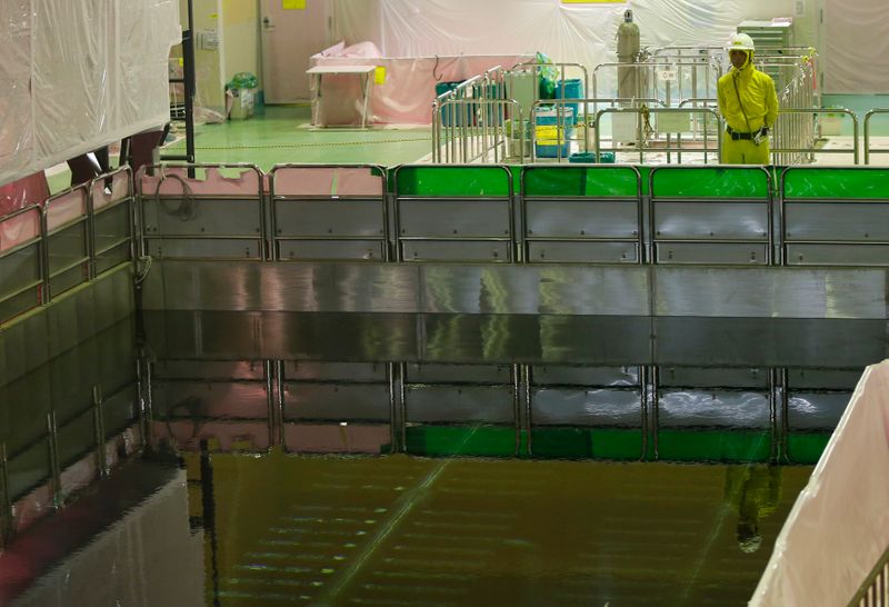 A worker stands next to a spent fuel pool on the top floor of the No.5 reactor building at Chubu Electric Power Co.'s Hamaoka Nuclear Power Station in Omaezaki
