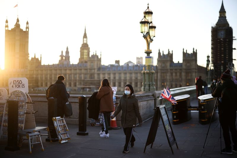 A person wearing a protective face mask walks over Westminster Bridge in London