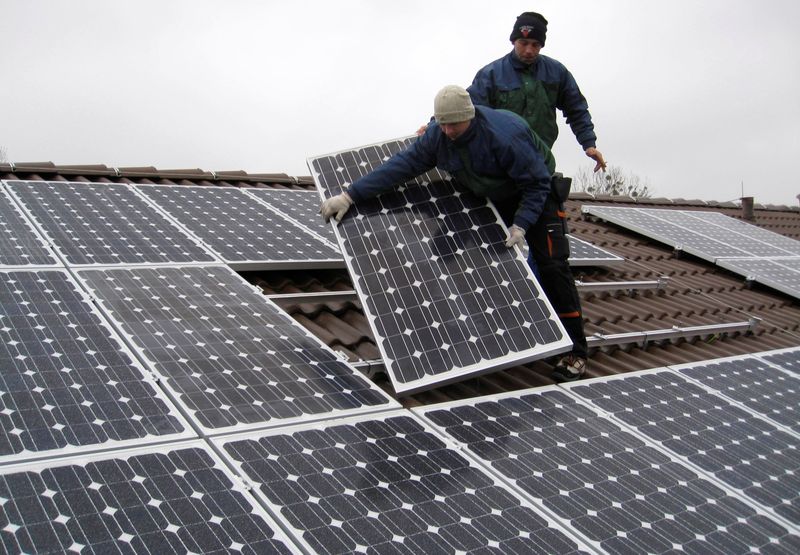 FILE PHOTO: Workers install solar panels on a roof near Berlin