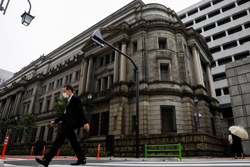 FILE PHOTO: A man wearing a protective mask walks past the headquarters of the Bank of Japan in Tokyo