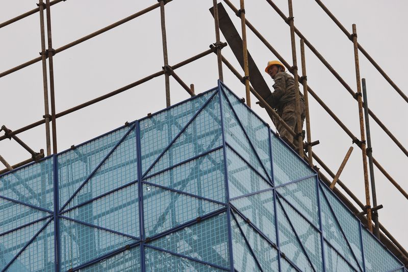 FILE PHOTO: A man walks on a scaffolding at the construction site of the Beijing Xishan Palace apartment complex developed by Kaisa Group Holdings Ltd in Beijing