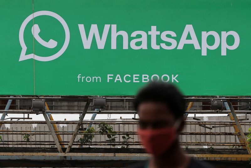 A man walks past a hoarding of the WhatsApp application installed at a skywalk in Mumbai