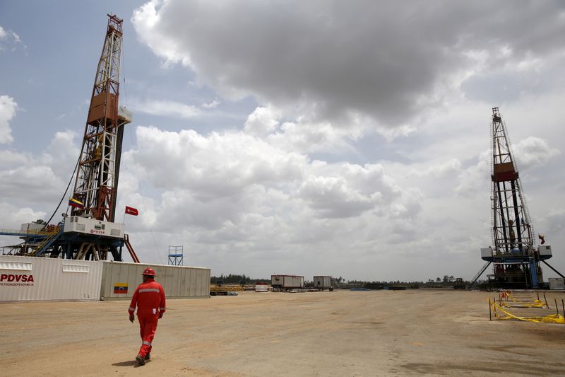 Un operaio cammina accanto alle piattaforme di perforazione in un pozzo di petrolio gestito dalla compagnia petrolifera statale venezuelana PDVSA,