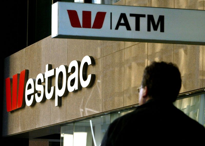FILE PHOTO: A pedestrian passes below signs for Westpac Bank during the company's strategy update meeting in cen..