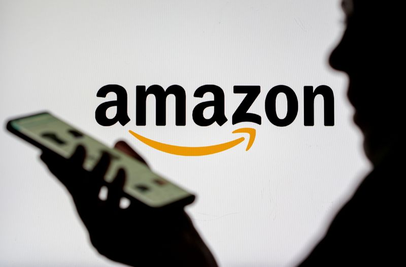 FILE PHOTO: Woman with smartphone is seen in front of displayed Amazon logo in this illustration taken