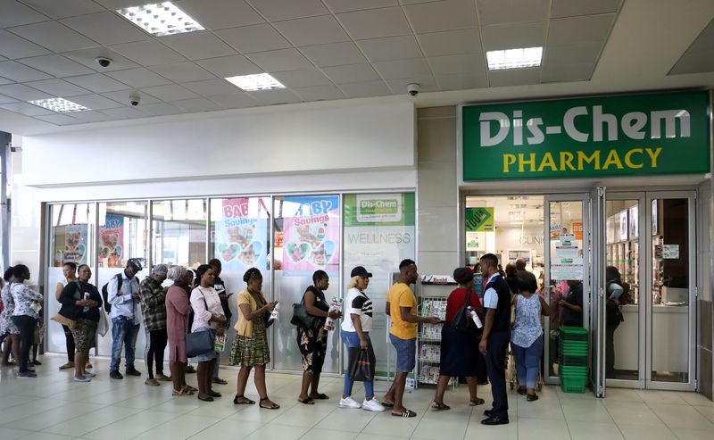 Shoppers queue outside a South African drugstore chain Dis-Chem Pharmacies ahead of a nationwide lockdown for 21 days to try to contain the coronavirus disease (COVID-19) outbreak, in Johannesburg