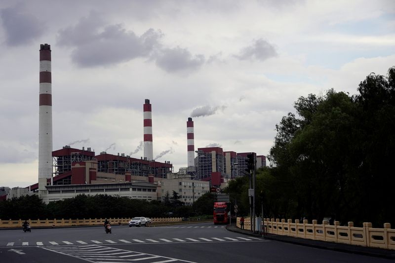 FILE PHOTO: People drive past a coal-fired power plant in Shanghai