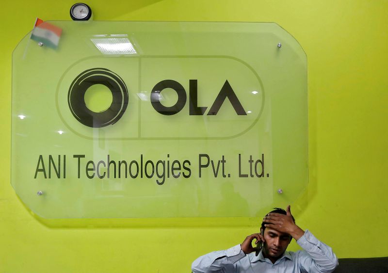 FILE PHOTO: An employee speaks over his phone as he sits at the front desk inside the office of Ola cab service in Gurugram