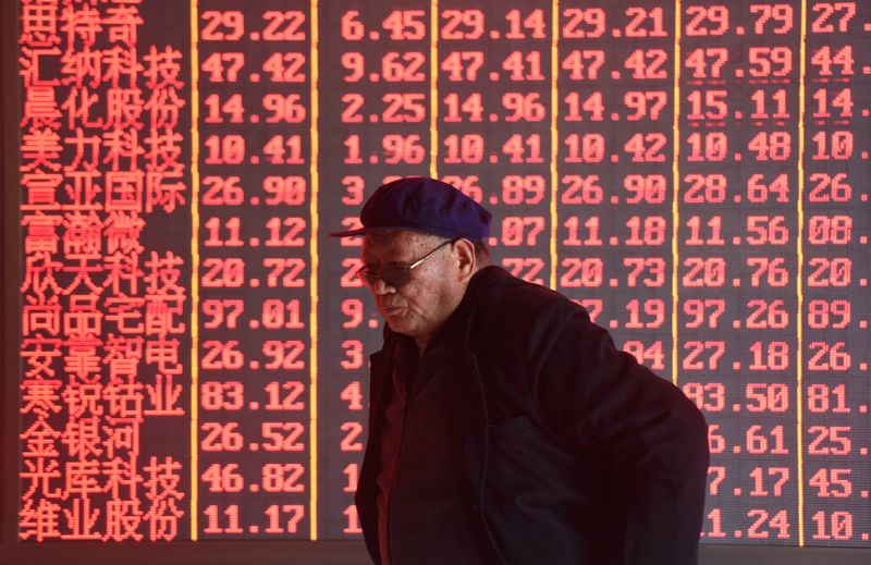 Man stands in front of an electronic board displaying stock information at a brokerage firm in Hangzhou
