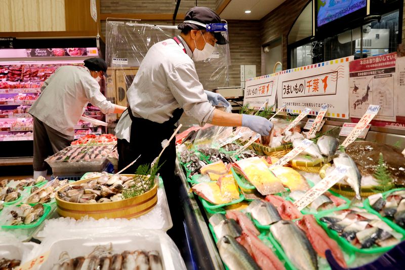 FILE PHOTO: A staff wearing a face shield sells fish at Japan's supermarket group Aeon's shopping mall as the mall reopens amid the coronavirus disease (COVID-19) outbreak in Chiba