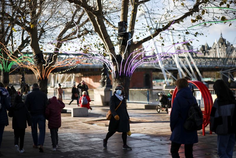 A person wearing a protective face mask walks past seasonal illuminations on the South Bank, amid the coronavirus disease (COVID-19) outbreak in London