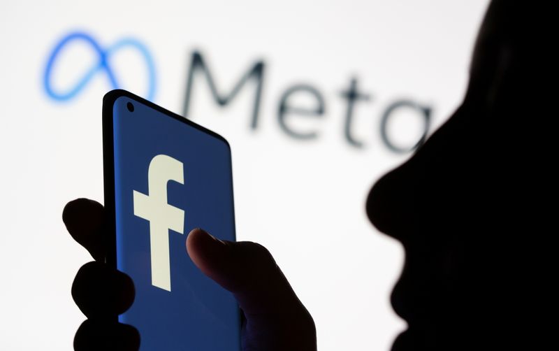 FILE PHOTO: Woman holds smartphone with Facebook logo in front of a displayed Facebook's new rebrand logo Meta in this illustration picture