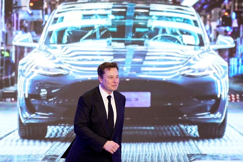 FILE PHOTO: Tesla Inc CEO Elon Musk walks next to a screen showing an image of Tesla Model 3 car during an opening ceremony for Tesla China-made Model Y program in Shanghai