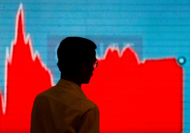 A man walks past a screen displaying news of markets update inside the Bombay Stock Exchange (BSE) building in Mumbai