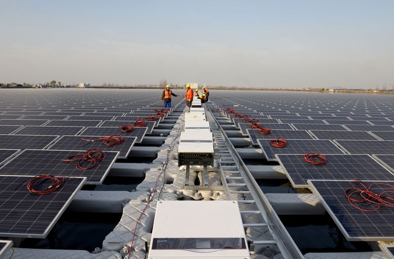 Workers install solar panels at a floating solar plant developed by China's Three Gorges Group, in Huainan