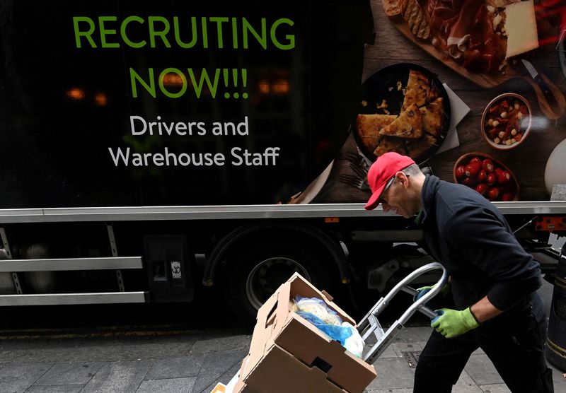 FILE PHOTO: Lorry driver passes a sign on the side of his vehicle advertising for jobs as he makes a delivery, in London