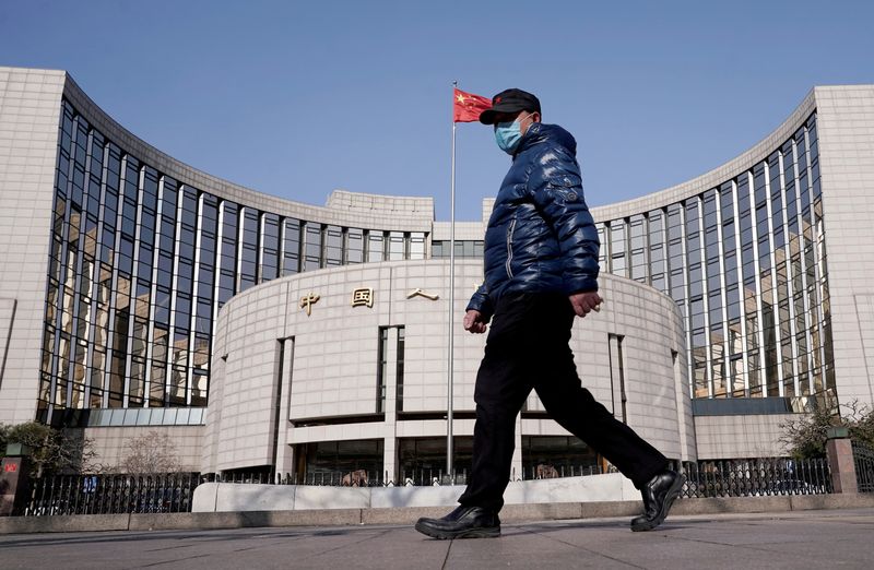 FILE PHOTO: FILE PHOTO: Man wearing a mask walks past the headquarters of the People's Bank of China, the central bank, in Beijing