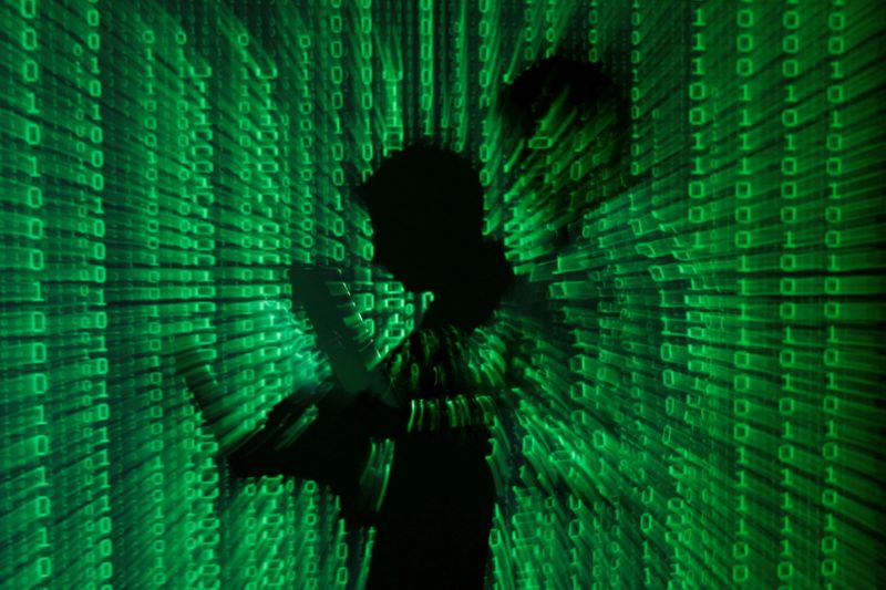 FILE PHOTO: An illustration picture shows projection of binary code on man holding laptop computer