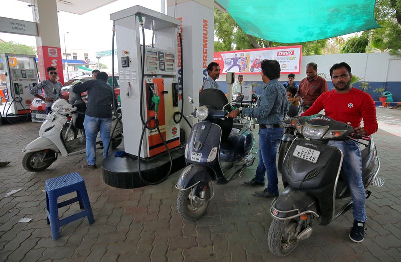 FILE PHOTO: People get their two-wheelers filled with petrol at a fuel station in Ahmedabad