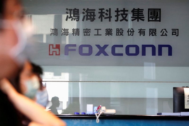 FILE PHOTO: People wear masks to protect themselves from coronavirus disease (COVID-19) while listening to the annual general meeting at the lobby of Foxconn's office in Taipei