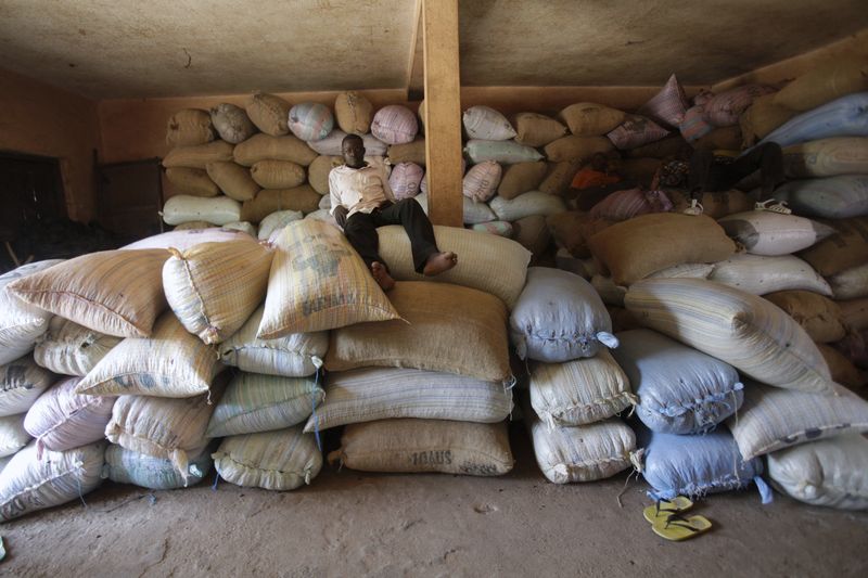 Workers sit on bags of cocoa inside a warehouse in Niable