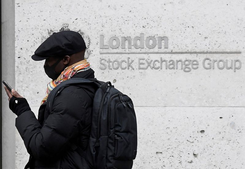 FILE PHOTO: A man wearing a protective face mask walks past the London Stock Exchange Group building in the City of London financial district, whilst British stocks tumble as investors fear that the coronavirus outbreak could stall the global economy