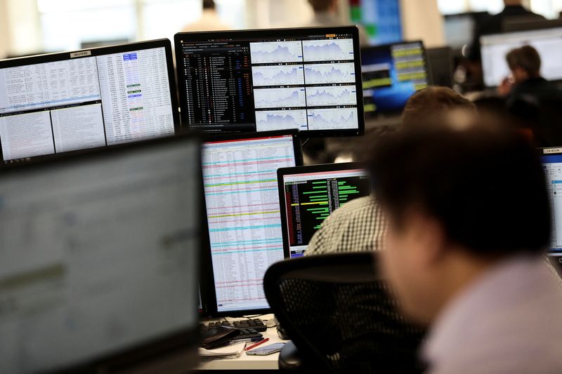 Traders looks at financial information on computer screens on the IG Index trading floor