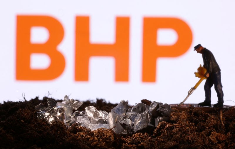 FILE PHOTO: Small toy figure and mineral imitation are seen in front of the BHP logo in this illustration