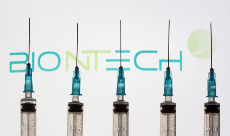FILE PHOTO: Syringes are seen in front of a displayed Biontech logo in this illustration