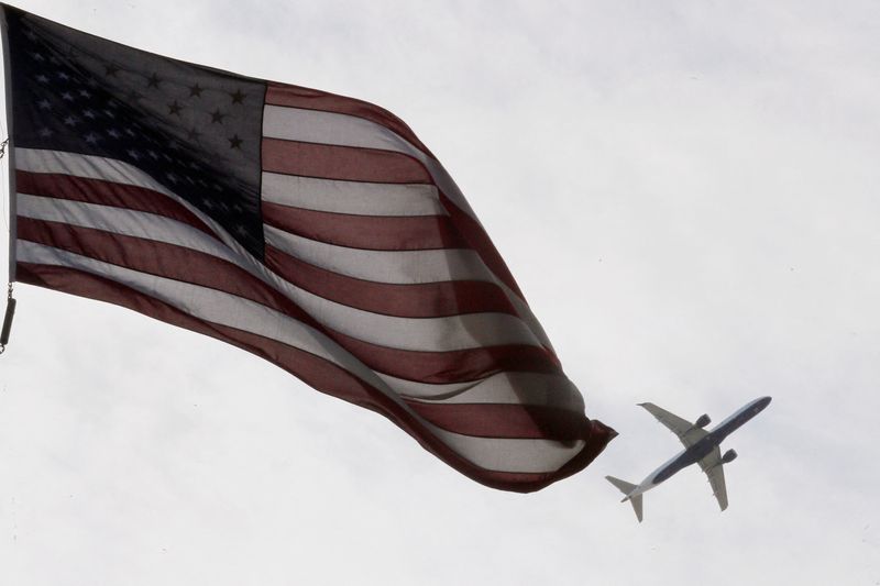A Delta Airlines flight takes off past a U.S. flag in Boston