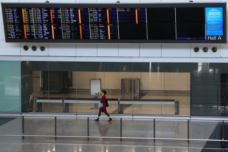 ARCHIV: Eine Flugbegleiterin vor einer Informationstafel in der Ankunftshalle des internationalen Flughafens von Hongkong, 11. Januar 2022. REUTERS/Lam Yik