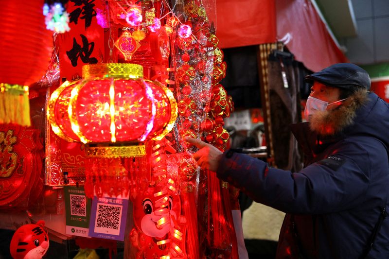 Un hombre con mascarilla observa varios objetos de decoración en un mercado de Pekín