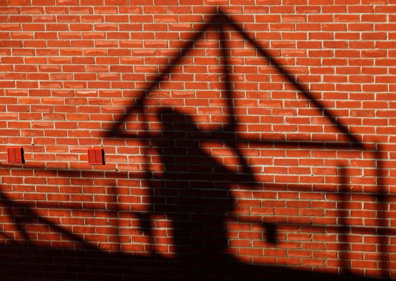 FILE PHOTO: A construction worker casts a shadow as he works on a Taylor Wimpey housing estate in Aylesbury