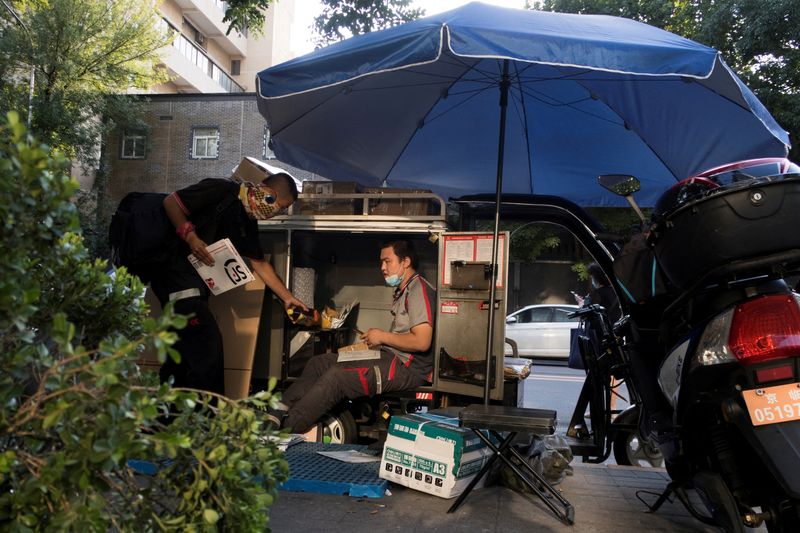 FOTO DE ARCHIVO: Un repartidor ordena paquetes en el maletero de su triciclo eléctrico en Pekín