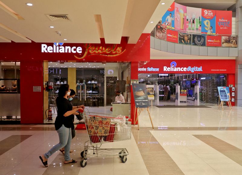 FILE PHOTO: Customers walk past stores of Reliance Industries Ltd, in Mumbai