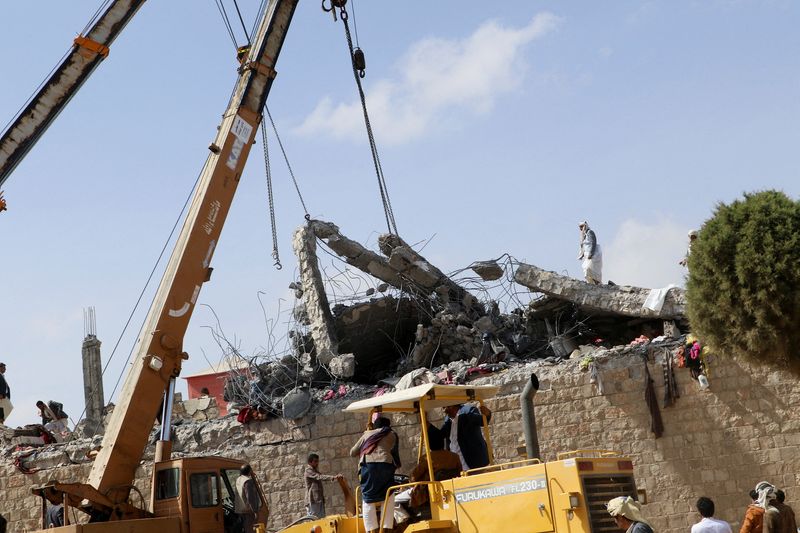 Rescuers use cranes to lift the collapsed roof of a detention center hit by air strikes, in Saada