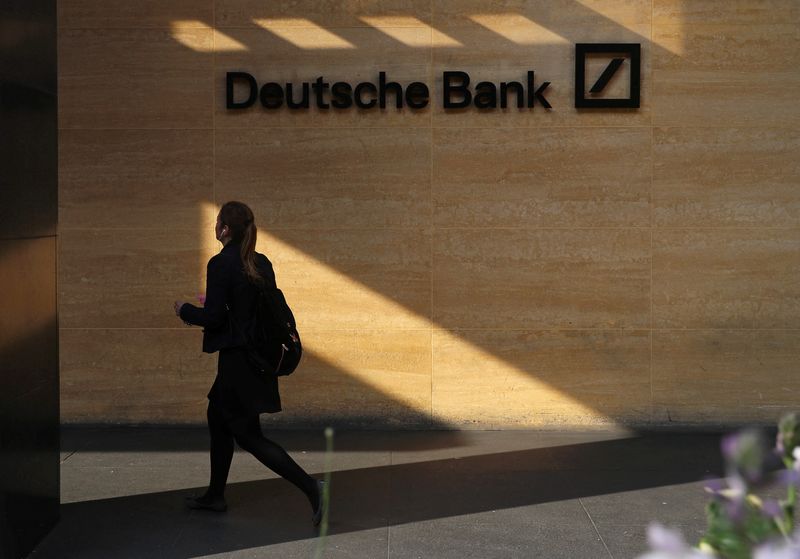 FILE PHOTO: A woman walks past a Deutsche Bank office in London