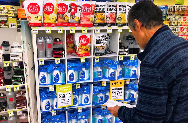 FILE PHOTO: A customer looks at products marked with discounted prices on display at a chemist in a shopping mall in central Sydney