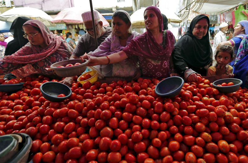 Local residents buy tomatoes from a roadside vegetable market in Ahmedabad, India