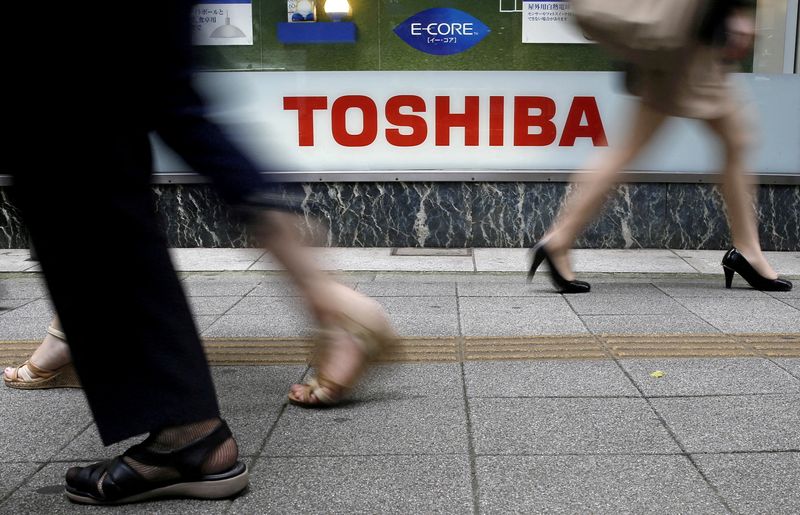 FILE PHOTO: Pedestrians walk past a Toshiba logo outside an electronics retailer in Tokyo
