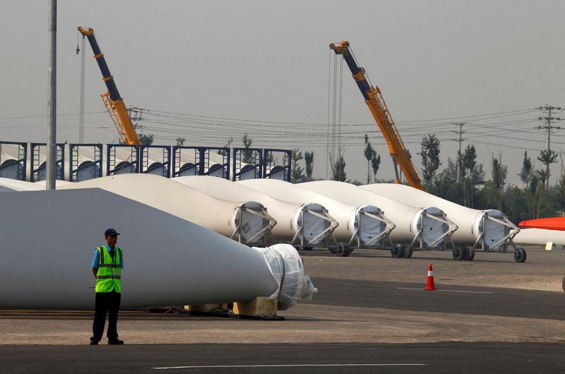 FILE PHOTO: A security guard stands next to blades and bases for wind turbines in the grounds of the Vestas Wind Technology company's factory in Tianjin, China