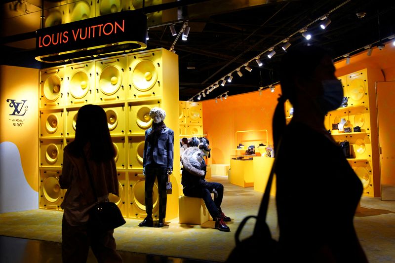 FILE PHOTO: Customers walk past a store of French luxury brand Louis Vuitton inside a shopping mall in Beijing