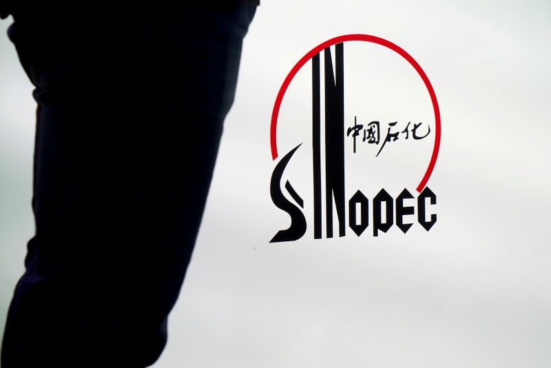 Man stands next to a logo of Sinopec at an expo on rubber technology in Shanghai