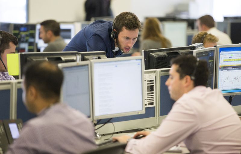 FILE PHOTO: Dealers work on the IG Group trading floor in London, Britain